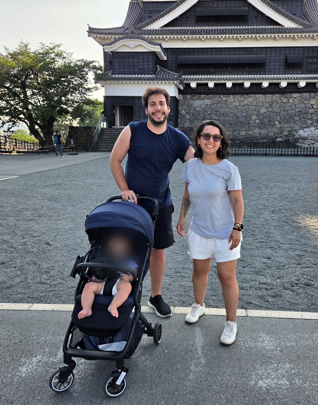 Adam e Rapha com o carrinho do bebê em frente à torre principal do Castelo de Kumamoto